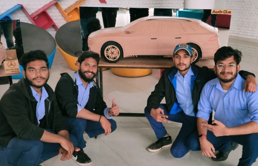 Jai with teammates around a car model
